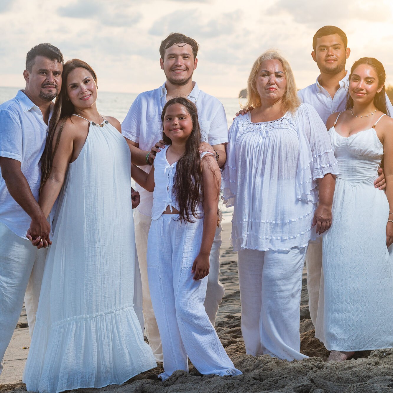 Extended family smiling together on the beach at sunset in Punta de Mita